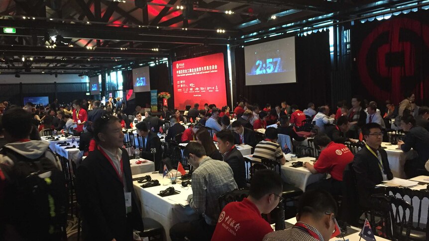 Hundreds of people working on tables in a large conference room