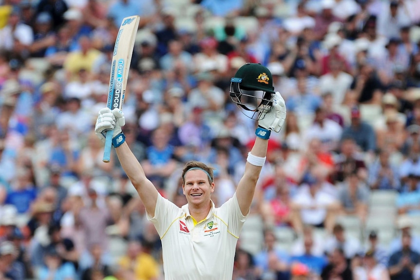 Steve Smith, with his bat in one hand and his helmet in the other, holds his arms aloft. He is smiling widely.