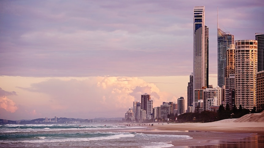Sunset on the beach at Surfers Paradise with crowds of people pictured in the far distance.