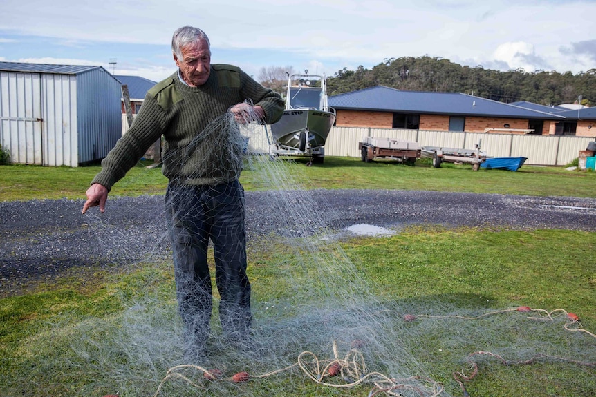 David 'Possum' Osborne inspects a large hole in a net caused by a seal.