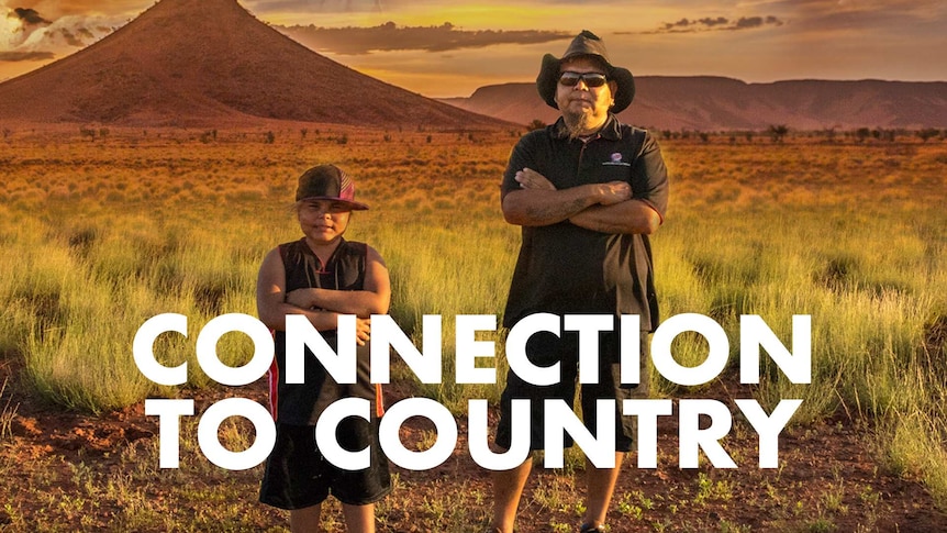 Indigenous man and his son standing in a dry, wide open field