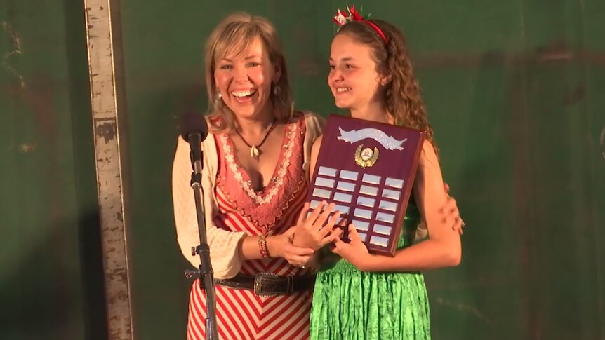 Felicity Urquhart presents an award to a young girl on stage.