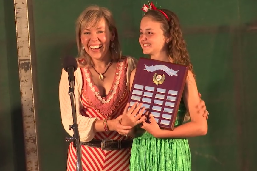 Felicity Urquhart presents an award to a young girl on stage.