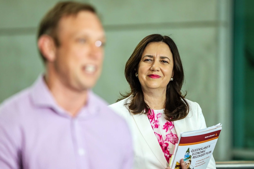 Annastacia Palaszczuk smiles at Steven Miles as he is talking