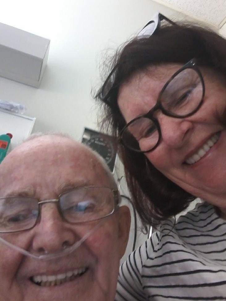 Selfie of older man and woman smiling, man has oxygen tube in his nose
