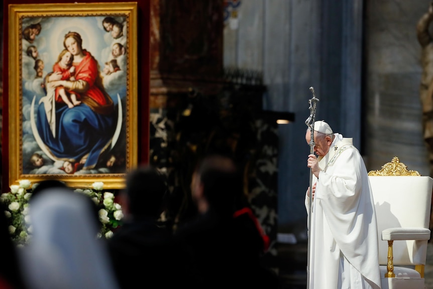 Pope Francis with his head bowed in front of a painting