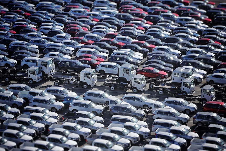 Scores of new car and truck imports, white, red and black,  parked on the wharf at the Port of Brisbane.