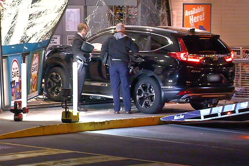The black SUV attached to a ramp to be towed away after smashing into the front window of the service station.
