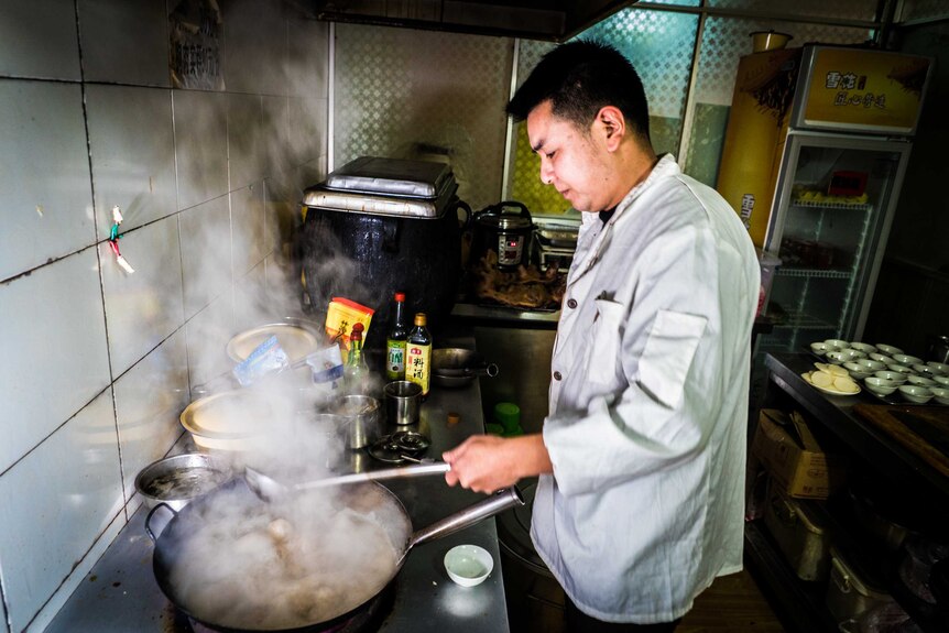 Wu Xianghai cooking dog meat in a wok at his restaurant in Guiyang.