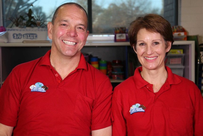 A man and woman in polo shirts smile at the camera