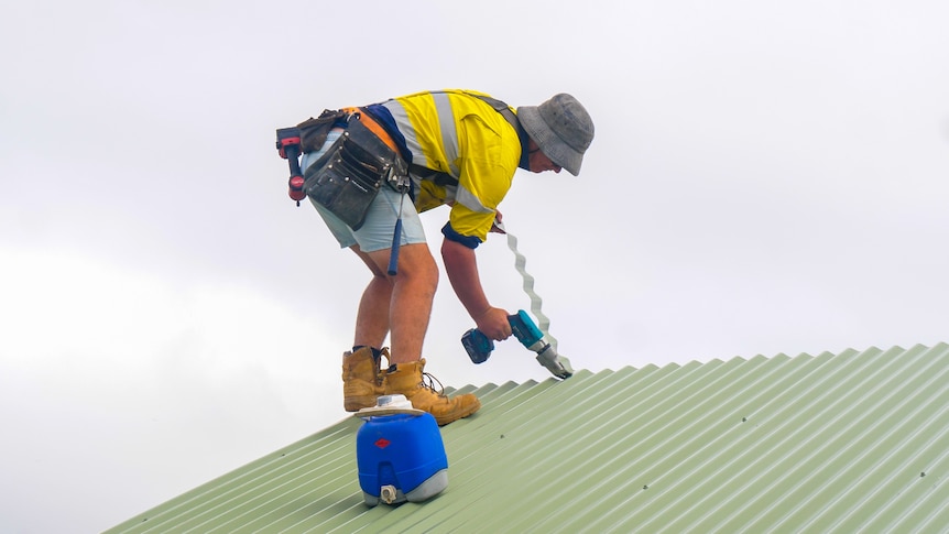 A builder repairing a roof with a drill.
