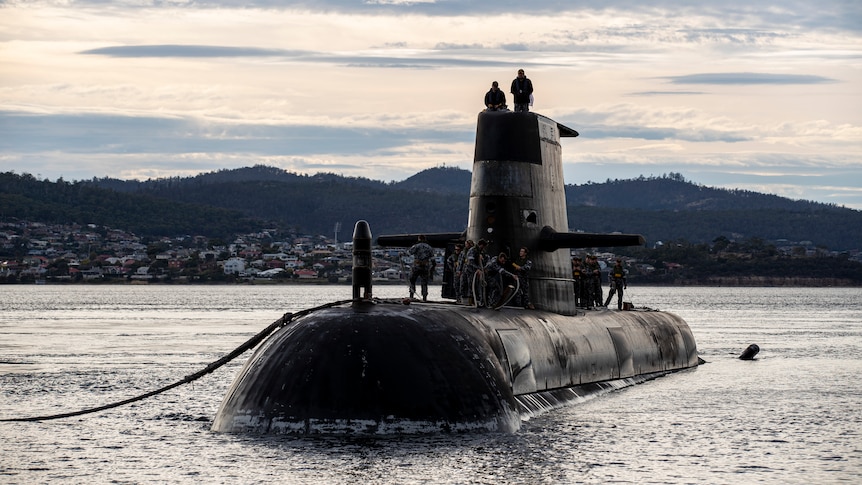 Crew stand on the top of a submarine.