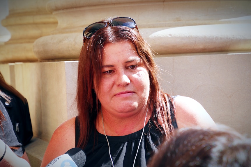 A woman wearing a black top and sunglasses on her head