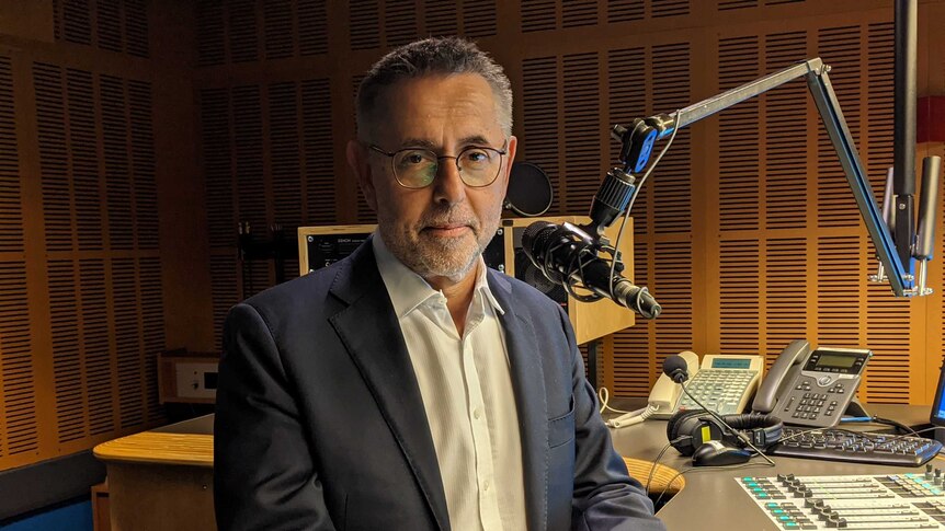 Swan in radio studio with microphone in front of his face.