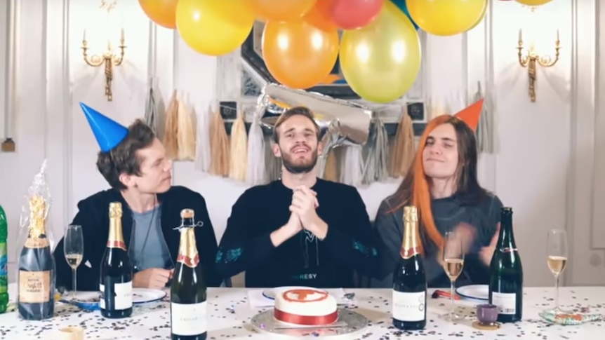 Joel Berghult, Felix Kjelberg and David Brown sit at a party table with balloons