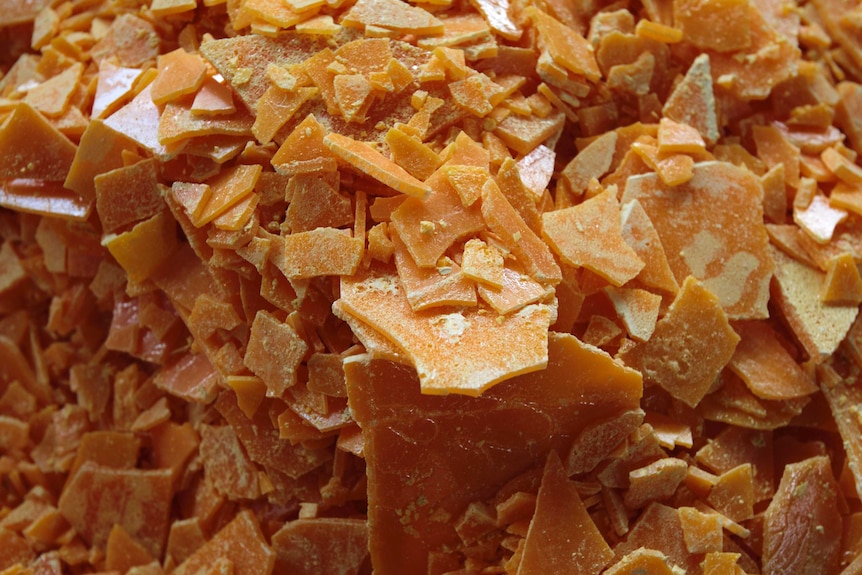 Wafers and chips of yellow-orange sulphur piled together.