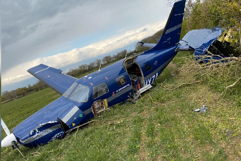 A small propeller-driven plan lies in pieces on a grassy field.