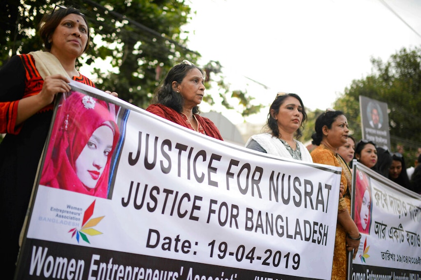 Women holding up banners with an image of a teenager in a red headscarf