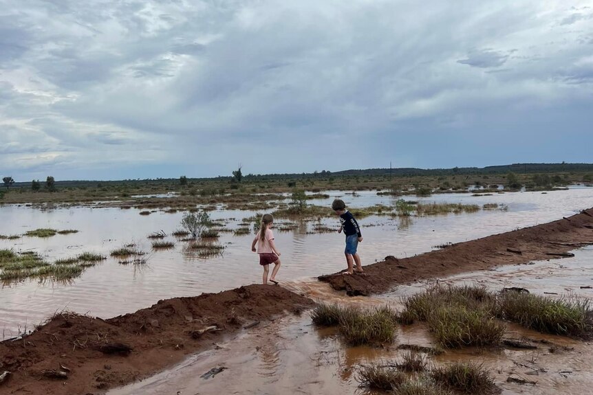 Two children, a boy and a girl, play in muddy waters in Western Queensland