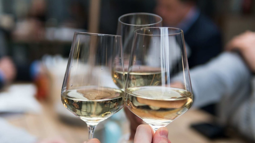 three people clinking their wine glasses