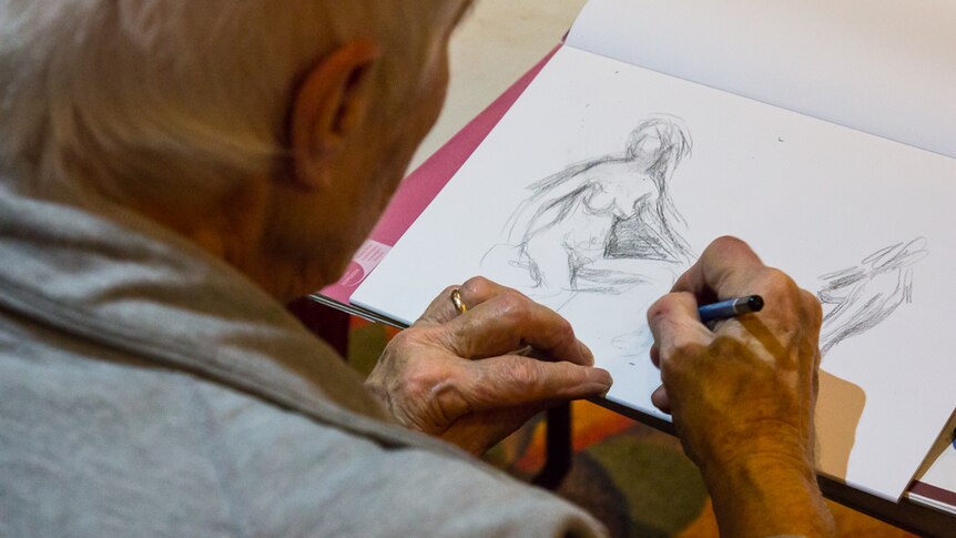 Woman drawing a nude female figure on a paper pad.