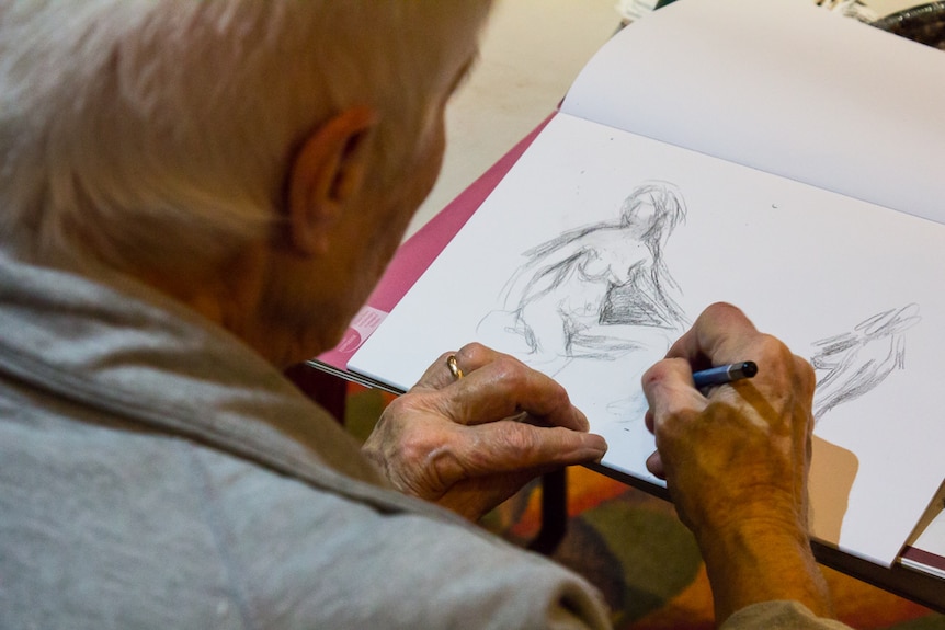 Woman drawing a nude female figure on a paper pad.