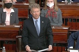 A white man in a suit stands to speak in the United States Senate.