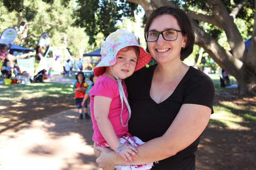 A woman wearing glasses holds her daughter.