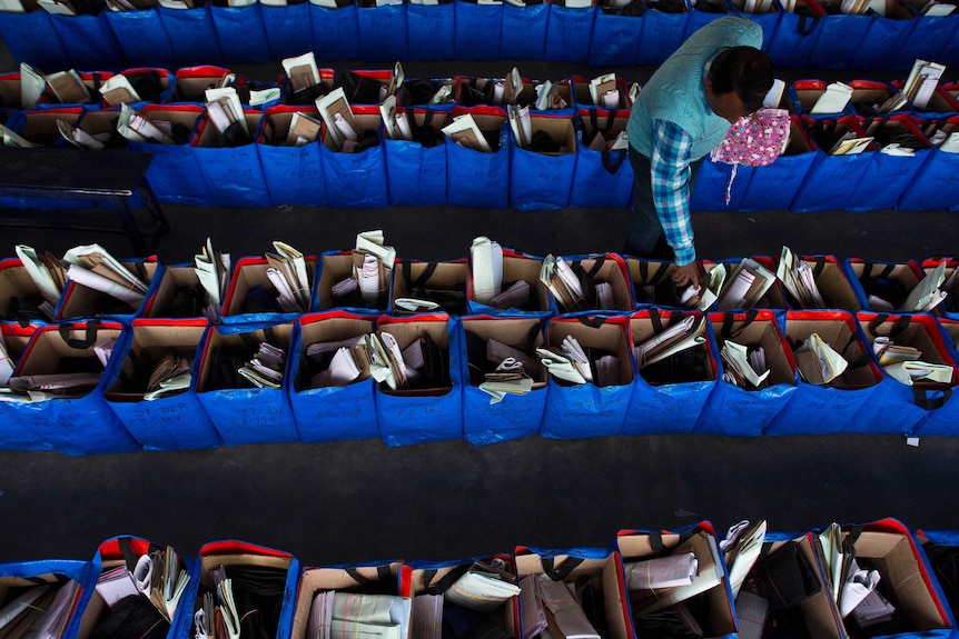 An Indian election official arranging many rows of voting material.