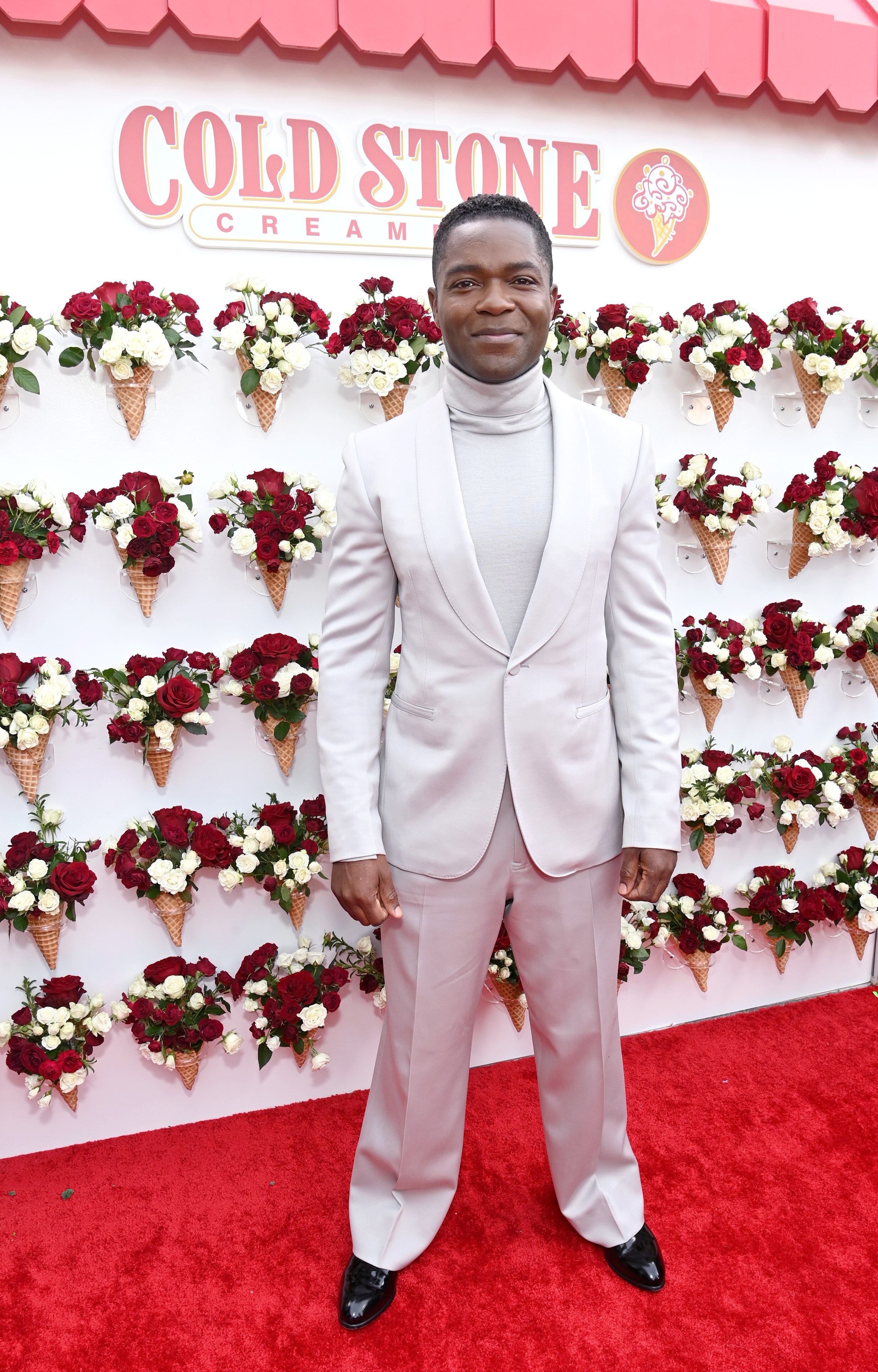 David Oyelowo wearing a light grey suit with a soft matching turtleneck shirt underneath