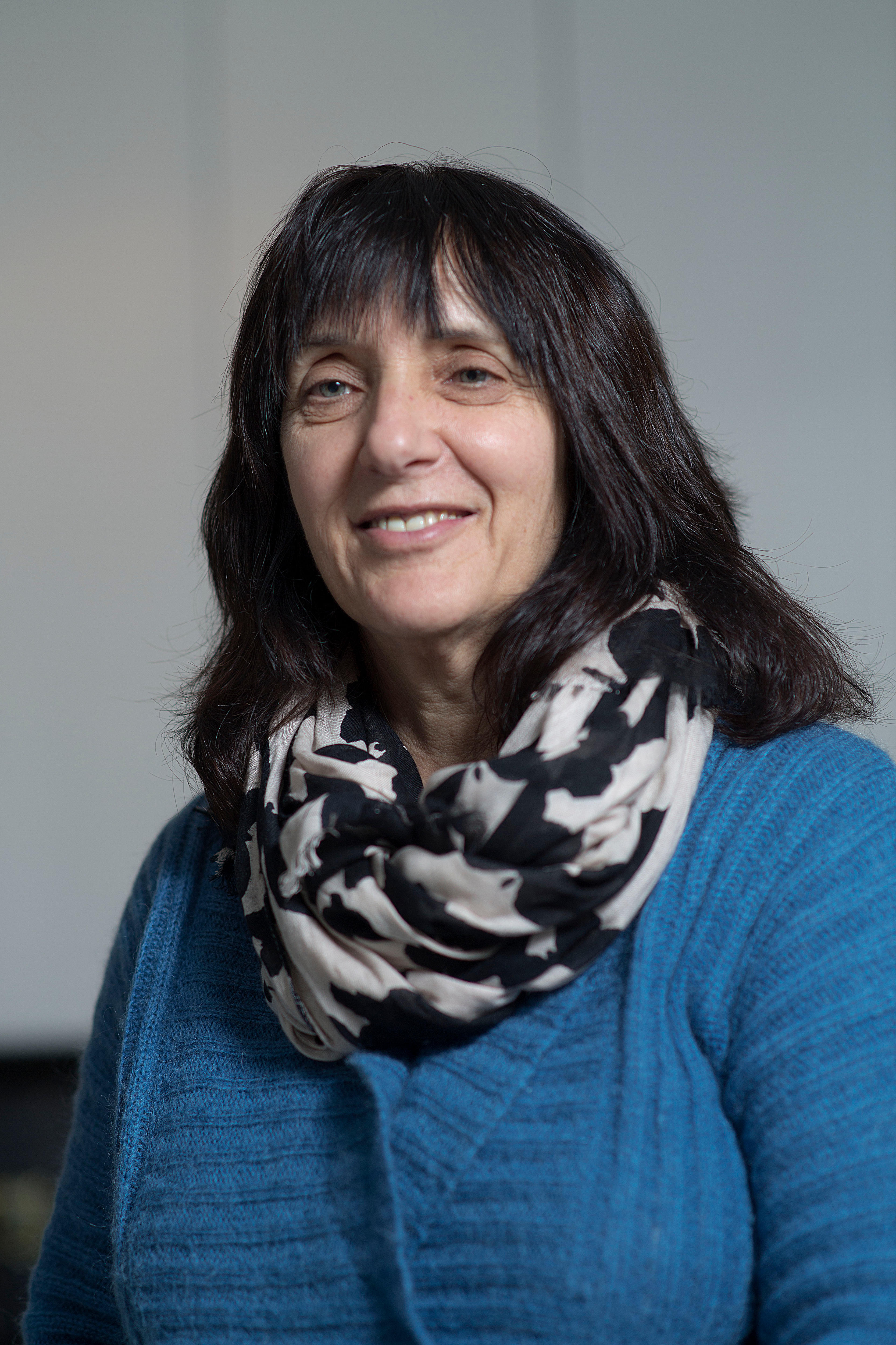 Cathy Kezelman wears a blue jumper and black and white scarf in front of a grey background