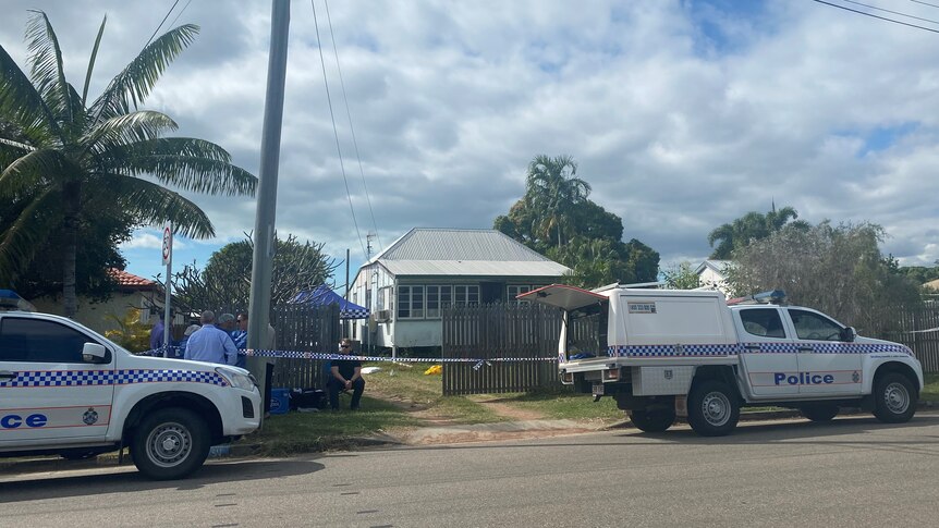 Two police vehicle parked outside a house surrounded by police tape