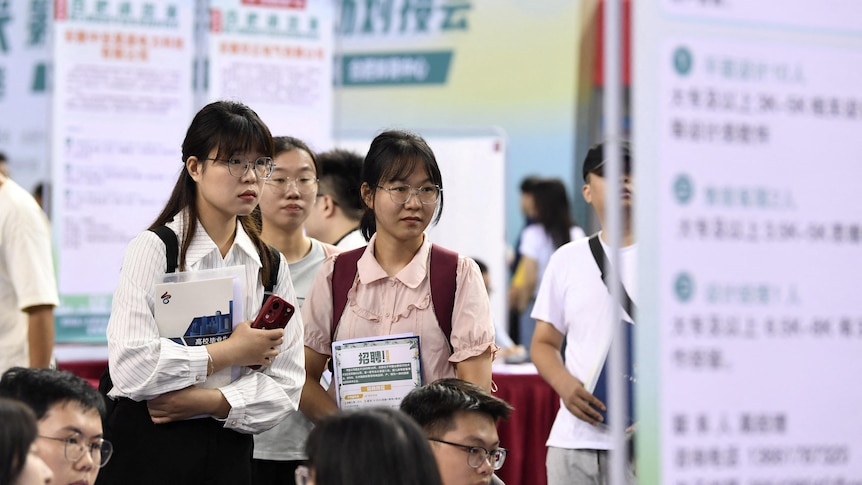 People attend a job fair for university graduates at a gymnasium