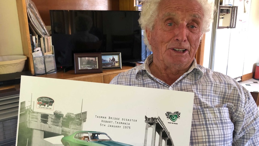 Frank Manley, Tasman Bridge disaster survivor, holds a poster commemorating the famous photo of his Holden Monaro