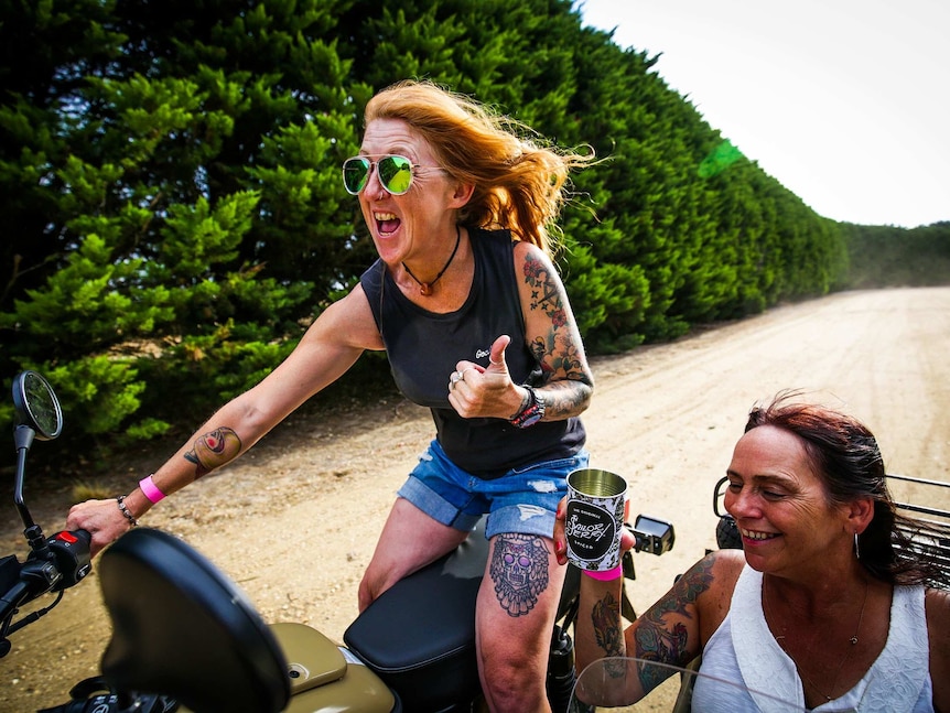 Kato hoons along a row of hedges with her friend riding in her side car