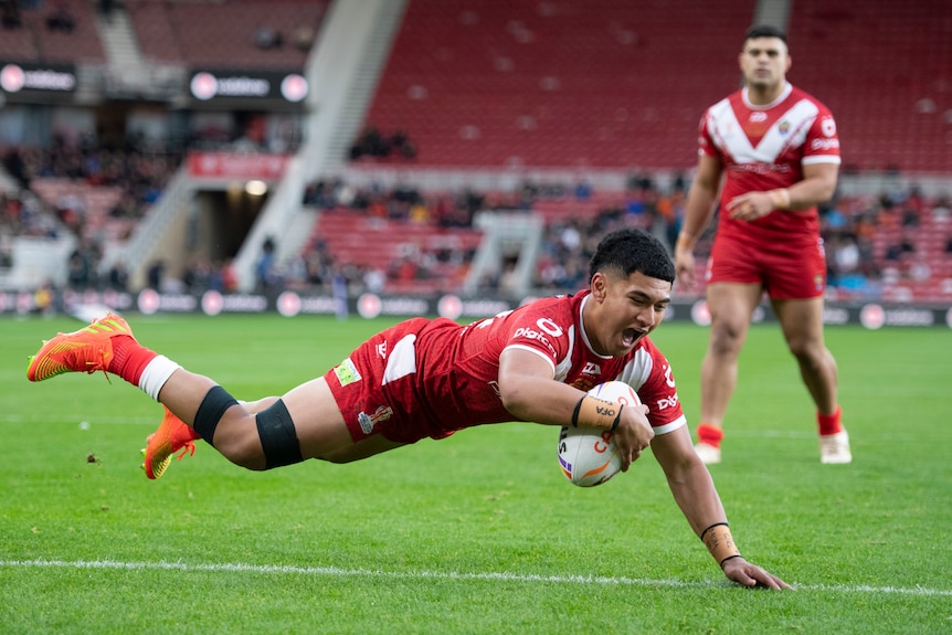 A player dives across the line to score a try in a rugby league match