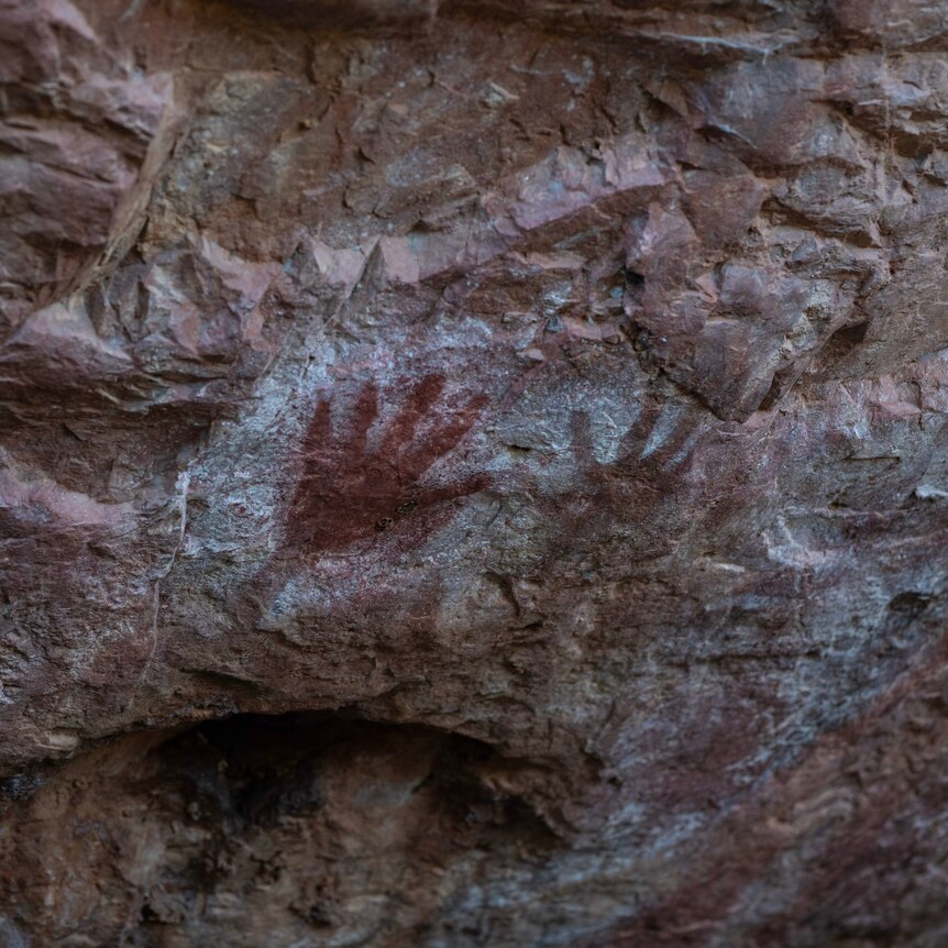 Hands stencilled on rock.