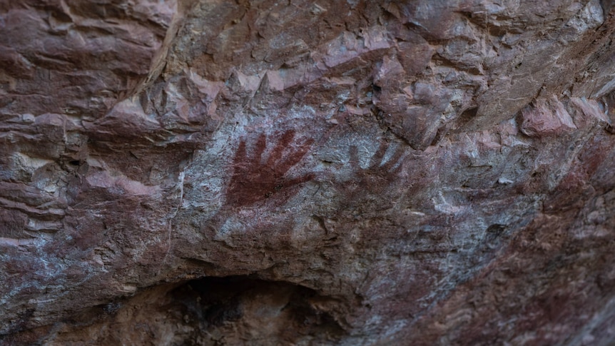 Hands stencilled on rock.