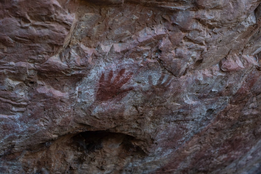 Hands stencilled on rock.