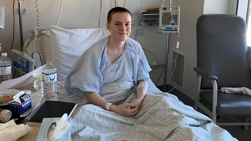 Lauren Anderson smiles white sitting up in a hospital bed.
