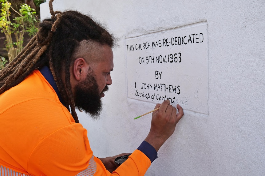 Man paints dedications words on to a wall