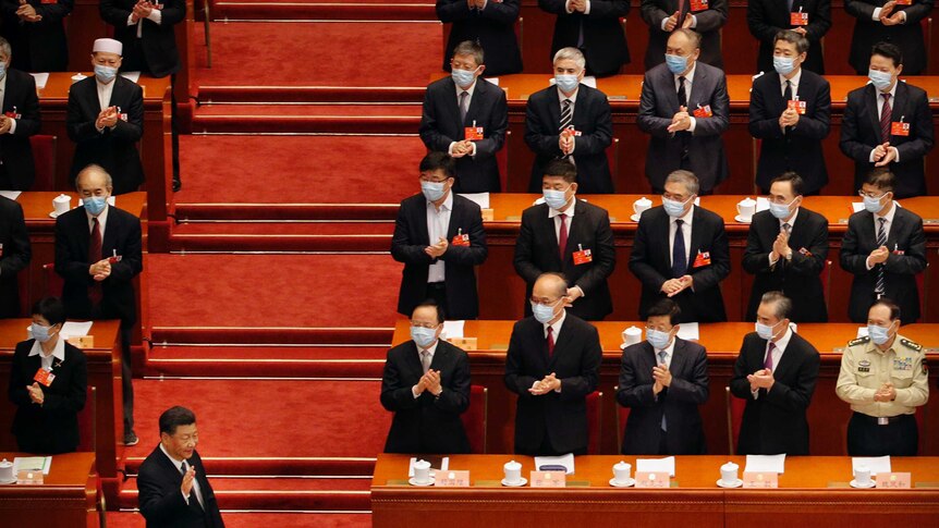 The parliamentary benches are lined with people wearing masks. Mr Xi, standing in front of them, does not