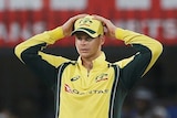 Australia's captain Steven Smith stands in the field with hands on head.