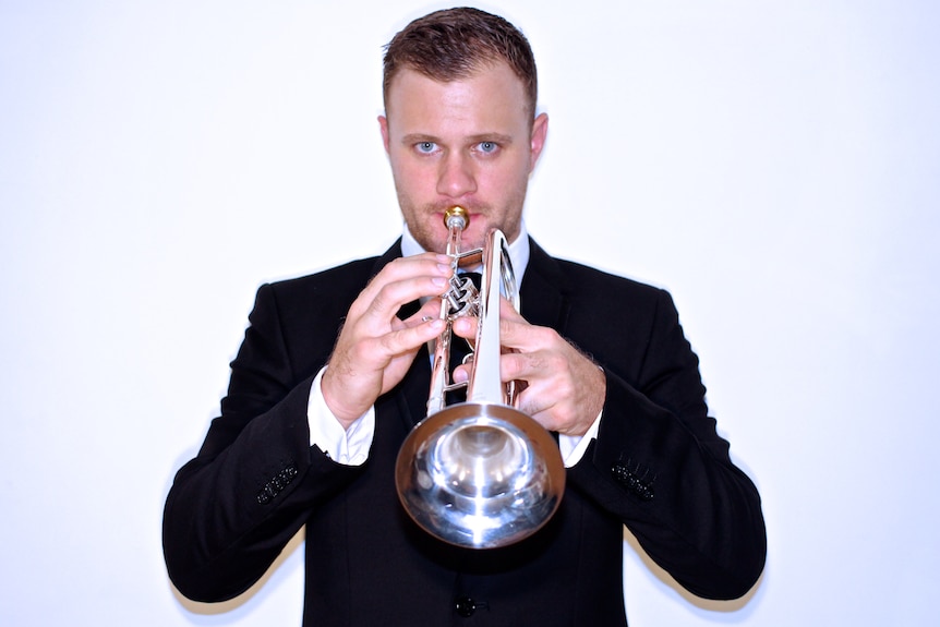 A young man in a suit playing the trumpet