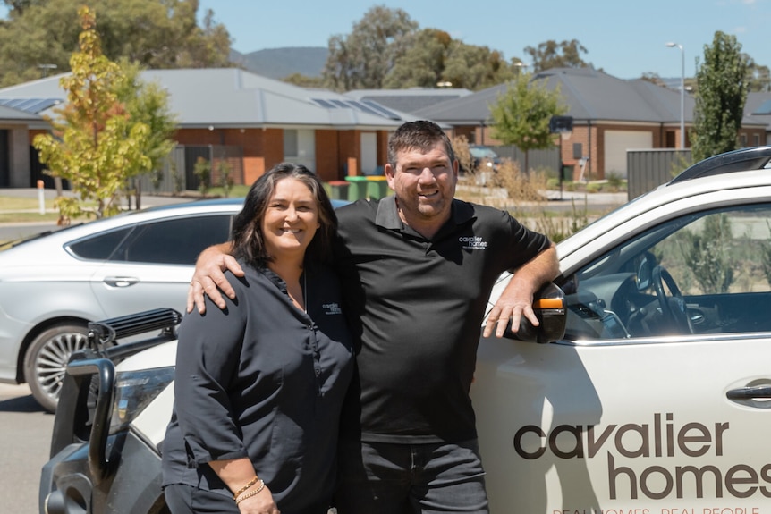 Man and woman standing in front of a car 