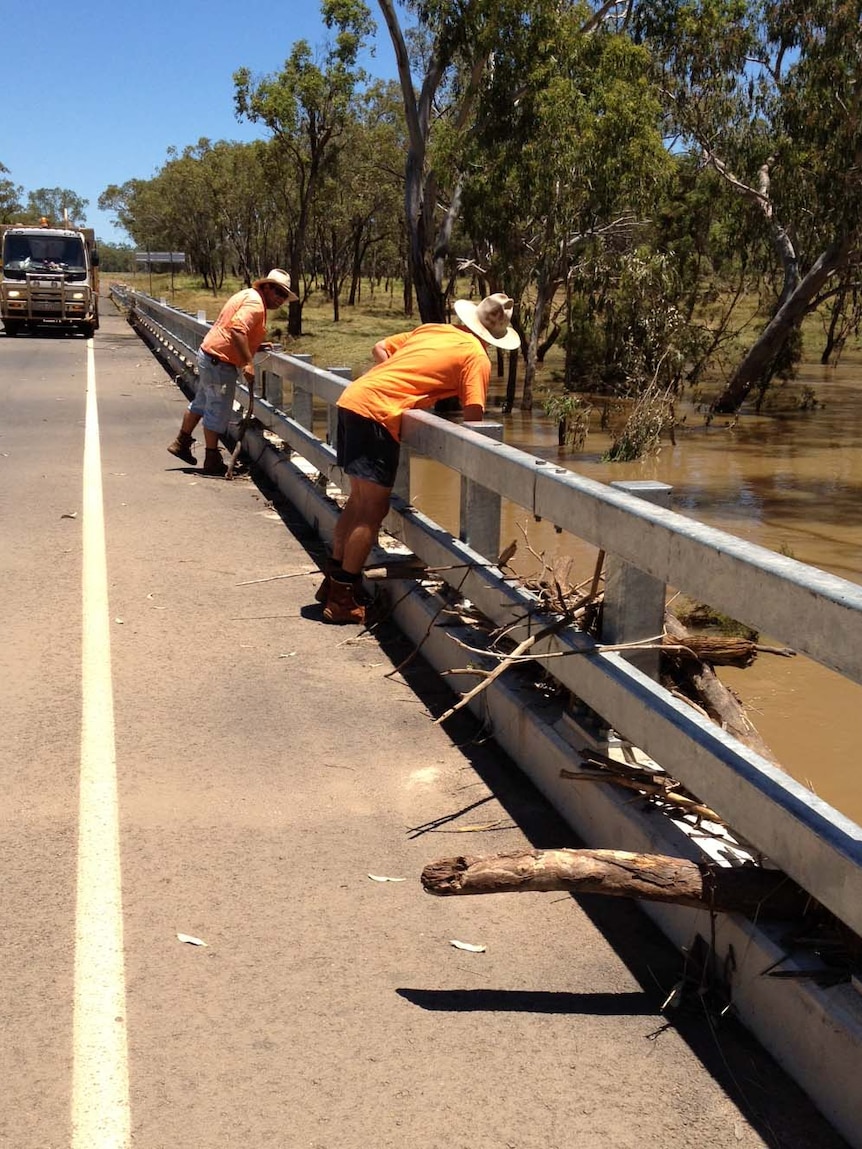 Workers survey the flood damage to a bridge on the Warrego Highway
