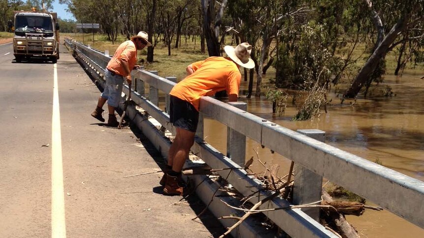 Workers survey the flood damage to a bridge on the Warrego Highway