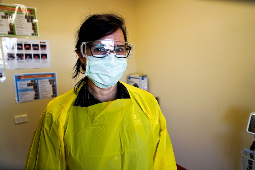 Carol Mackrow is wearing full PPE and smiling under a mask.