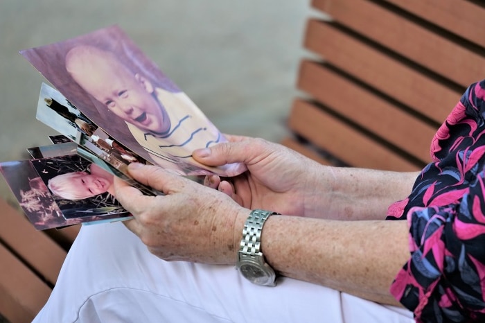 A woman looking at old printed photos of toddler.