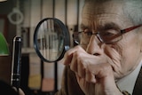An elderly man with a magnifying glass, the spy Sergio Chamy in documentary The Mole Agent